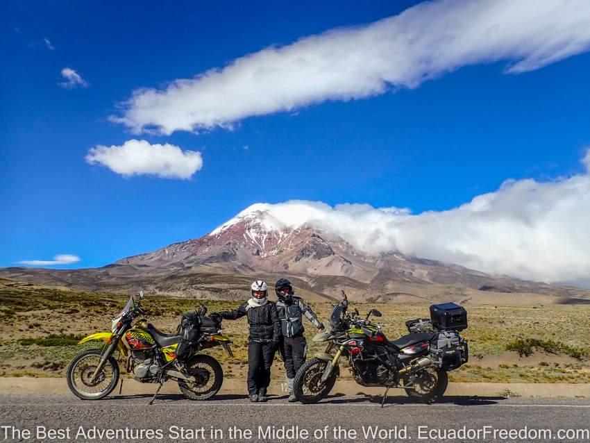 man and woman standing with two adventure motorcycles in front on chimborazo