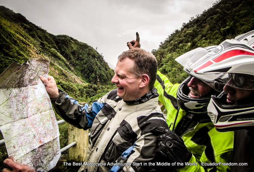 three adventure motorcyclists holding up a map lost in Ecuador