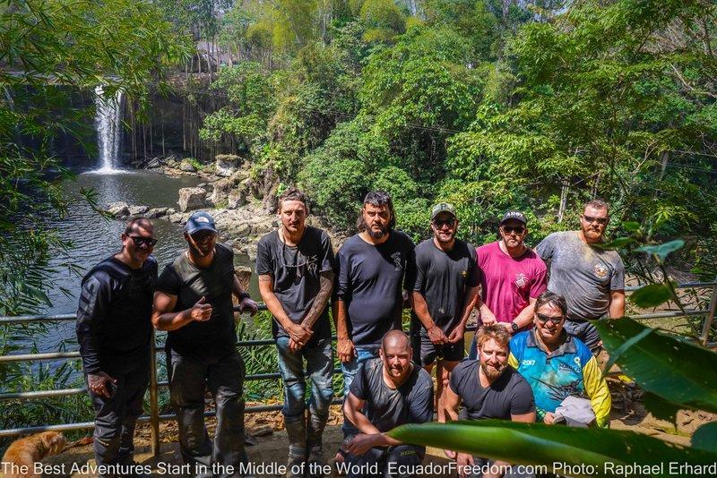 group of friends on a motorcycle adventure tour in ecuador posing in front of a waterfall