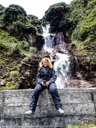 woman motorcyclist sitting in front of a waterfall in sangay national park in ecuador