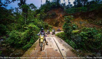 coastal rainforest in ecuador with enduro motorcycles crossing a metal bridge