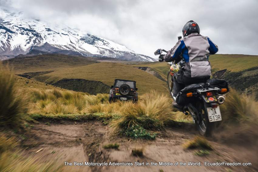 doing a wheelie on a suzuki DR650 with a jeep and chimborazo volcano in the foreground