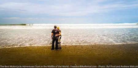 couple in motorcycle gear embracing on a beach in ecuador