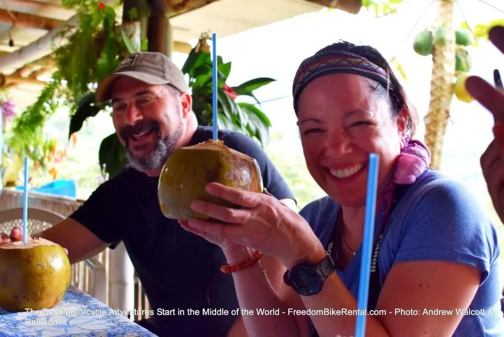 two happy motorcyclists drinking coconut water in Ecuador