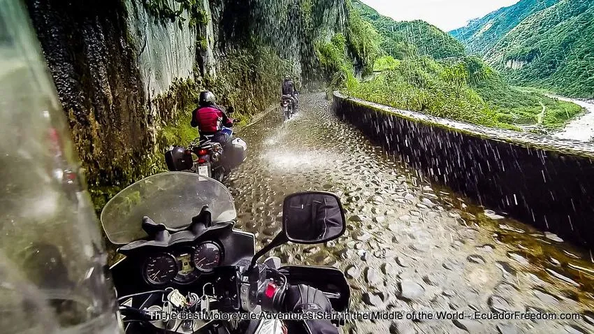 riding motorcycle to banos under waterfall