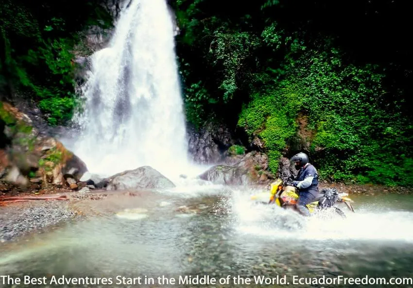 motorcycle crossing river with waterfall in ecuador