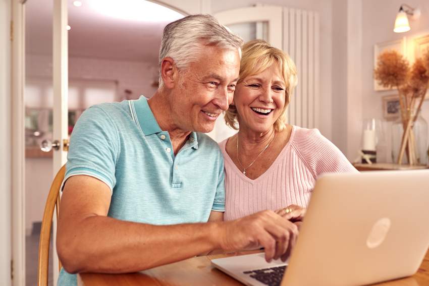 senior retired couple sitting on sofa at home booking a motorcycle tour